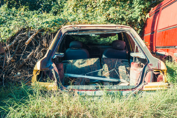 老旧的，被遗弃的，被毁坏的，被剥夺了零件的汽车被遗弃在草地上生锈图片下载