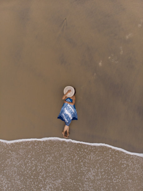 一个亚洲女性躺在沙滩上的航拍照片图片下载