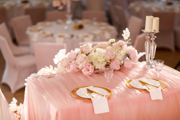 餐厅内粉红色桌布、水晶烛台、白色粉色花朵装饰。时髦的婚礼。用金盘、刀叉摆放餐桌图片下载
