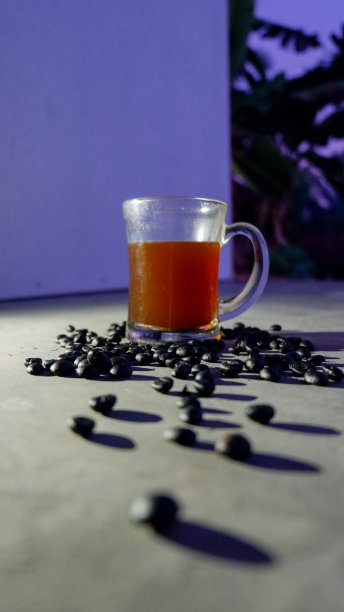 一杯黑咖啡，用玻璃杯盛着，周围撒着一些烤过的咖啡豆图片下载