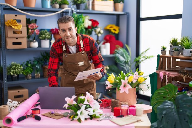 年轻的白人男子在花店用笔记本电脑阅读文件图片下载