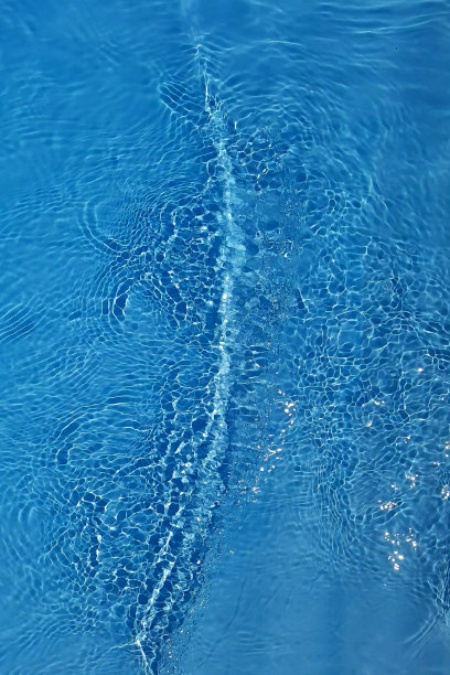 离焦模糊透明蓝色清澈平静的水面纹理与飞溅和气泡。新潮抽象的自然背景。阳光下的水波与复制空间。蓝色水彩闪闪发光图片下载