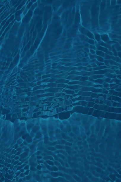 离焦模糊透明蓝色清澈平静的水面纹理与飞溅和气泡。新潮抽象的自然背景。阳光下的水波与复制空间。蓝色水彩闪闪发光图片下载