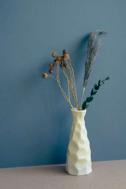 桌上的干花花瓶。深蓝色的墙壁背景。室内设计图片下载