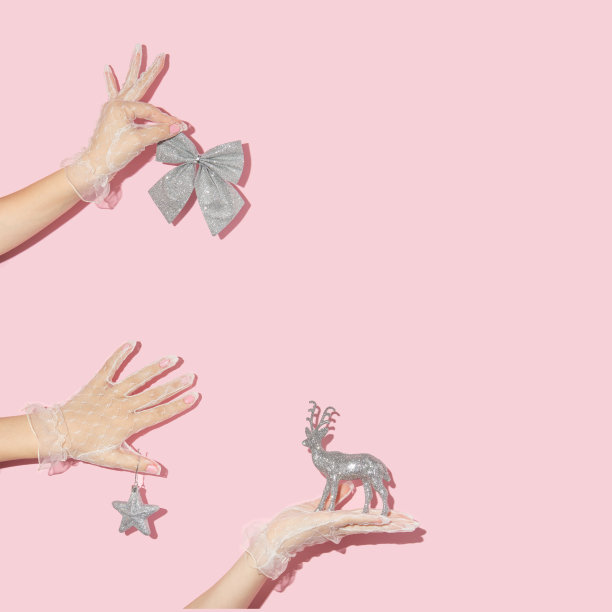 圣诞和新年的创意图案与手在蕾丝手套持有圣诞装饰在柔和的粉色背景。八九十年代复古时尚审美的庆祝理念。图片下载