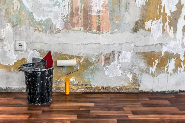 一个装着建筑工具的桶和一个油漆滚筒的空房间，旧的破旧的墙壁没有墙纸，只有一个欧式插座图片下载
