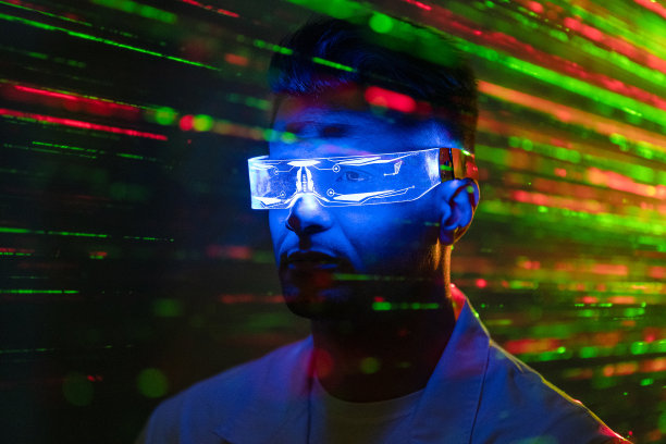 戴着未来主义眼镜的英俊男子站在激光束背景上图片下载