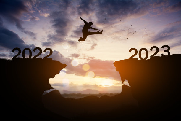 人的剪影在日落时跳到2023年的新年。图片下载