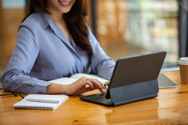 一个美丽的女人在咖啡店工作，手里拿着电脑、手机、平板电脑，早上在咖啡店，心情愉快，面带微笑。图片下载