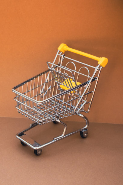 空的购物车在米色背景。为你的文本复制空间。网上购物，买商场市场商店的消费观念。小型玩具超市杂货推车。粮食危机。食品价格上涨，杂货价格上涨图片下载