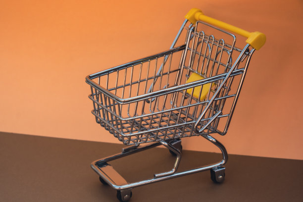 空的购物车在米色背景。为你的文本复制空间。网上购物，买商场市场商店的消费观念。小型玩具超市杂货推车。粮食危机。食品价格上涨，杂货价格上涨图片下载