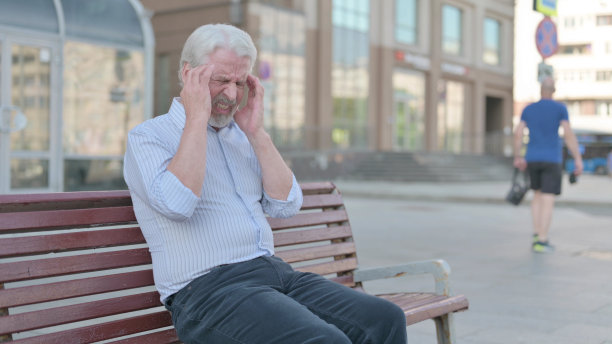 头痛老人坐在户外长凳上图片下载