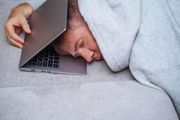 疲惫的商人睡在沙发上的笔记本电脑上，图片下载