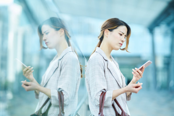 一名女子看着智能手机屏幕，脸上带着困惑的表情图片下载