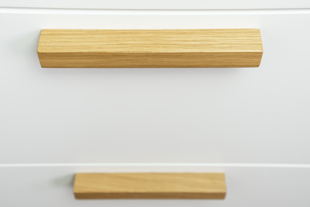白色抽屉柜上的家具把手。家具配件采用天然橡木，现代生态风格。图片下载