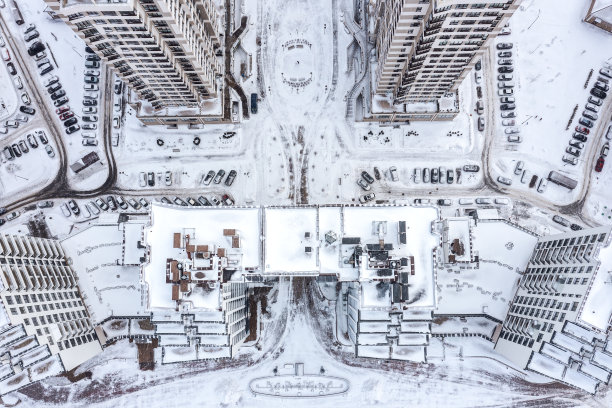 冬天的城市。白雪覆盖的公寓楼，屋顶，停着汽车的院子。鸟瞰图。图片下载