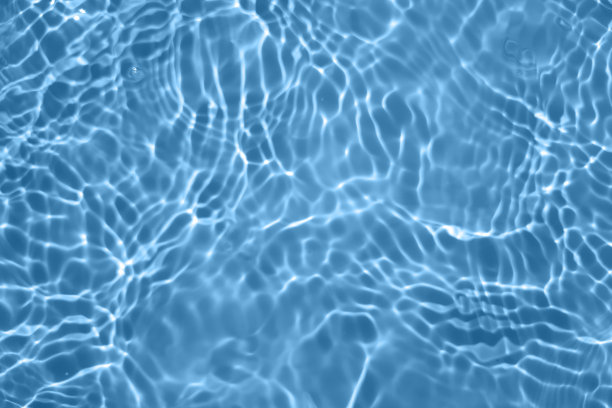 离焦模糊透明蓝色清澈平静的水面纹理与飞溅和气泡。新潮抽象的自然背景。阳光下的水波与复制空间。蓝色水彩闪闪发光图片下载