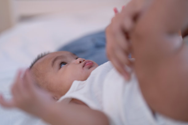 亚洲婴儿，刚出生的婴儿躺在床上，妈妈已经换了衬衫图片下载