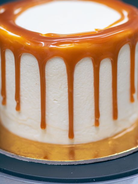 面包师傅用黑色手套用奶油和咸焦糖装饰纸杯蛋糕图片下载