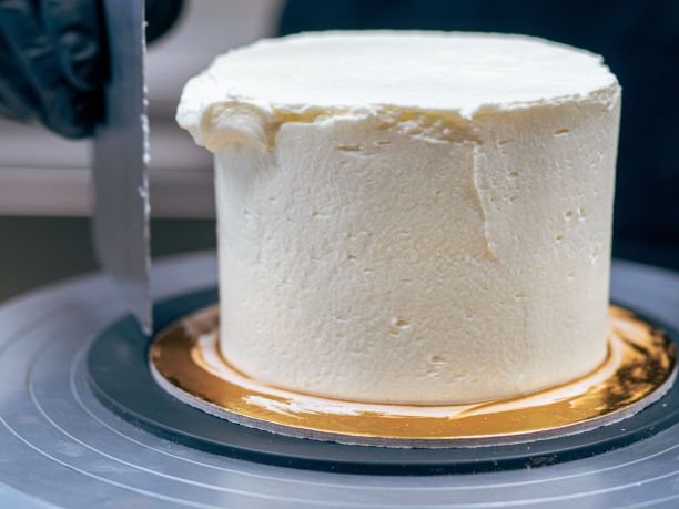 面包师傅用黑色手套用奶油和咸焦糖装饰纸杯蛋糕图片下载