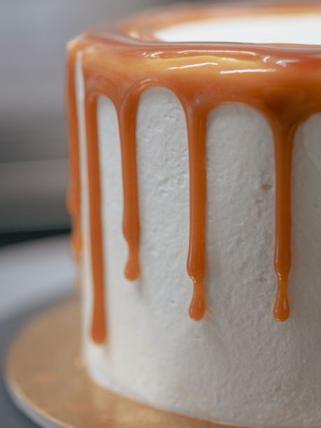 面包师傅用黑色手套用奶油和咸焦糖装饰纸杯蛋糕图片下载