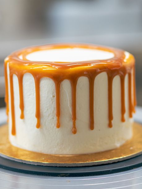 面包师傅用黑色手套用奶油和咸焦糖装饰纸杯蛋糕图片下载