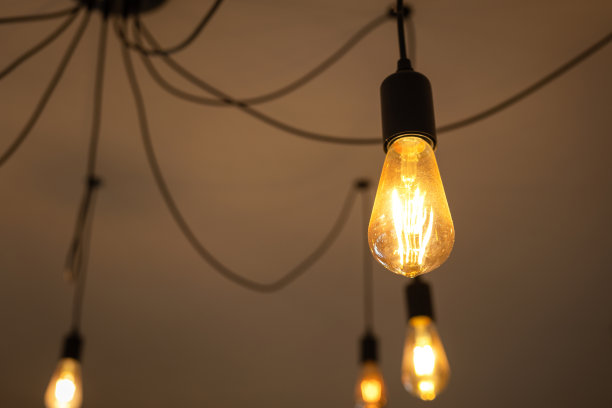 在温暖的光线下发光的天花板灯泡。图片下载