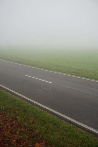 一个雾蒙蒙的早晨，在一条蜿蜒的路上。在一个雾蒙蒙的秋日早晨，有路标的铺好的路。这条路在雾中向右转。秋日清晨雾蒙蒙的路上。在雾中转过身来。图片下载