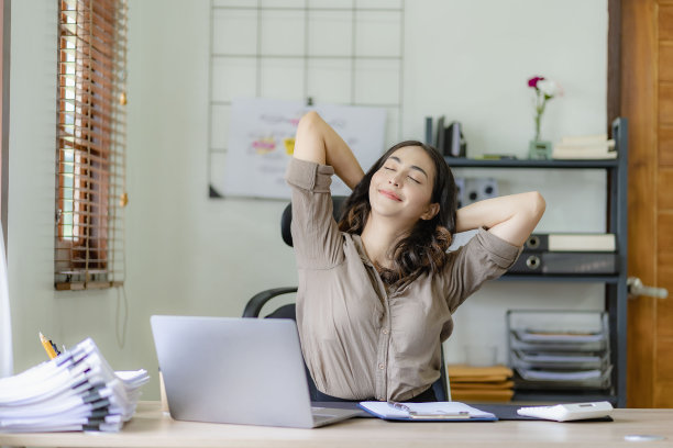 美丽年轻的亚洲女商人或女会计在工作中感到疲劳，在她的账目报告工作中伸展她的手。图片下载