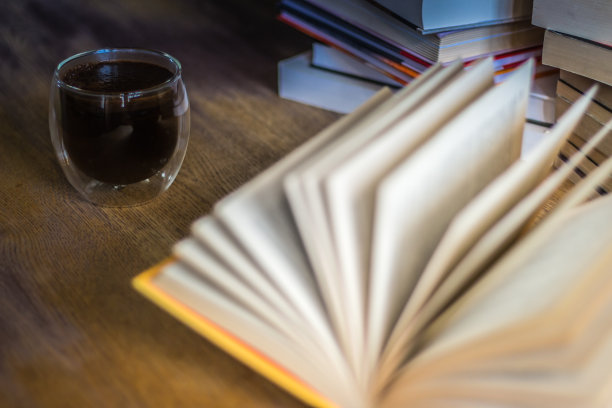 一堆旧书和咖啡杯。文学背景。打开书，桌上有一堆书。图书馆的咖啡时间。复古书和浓缩咖啡。图片下载