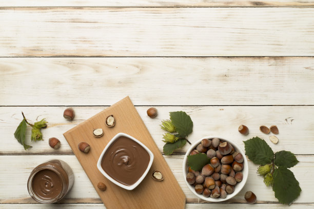 榛子奶油坚果和绿叶在木制背景，俯视图图片下载
