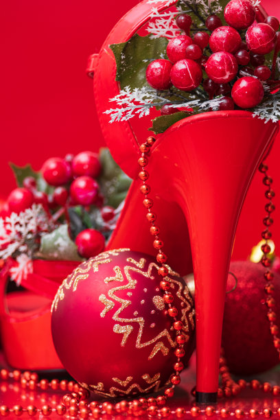 女性闪亮漆红色细高跟凉鞋和圣诞装饰与圣诞玩具特写在红色背景图片下载