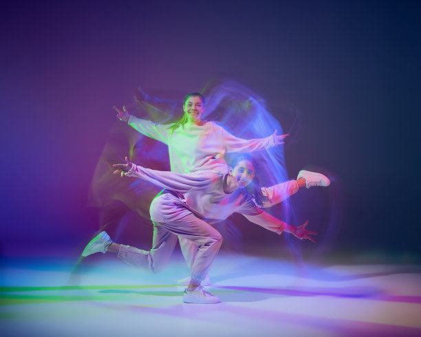 年轻女孩跳街舞的肖像孤立在渐变蓝紫色背景霓虹与混合光。性能图片下载