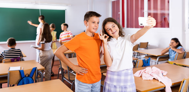 欢快的小女生在课堂上和同学用手机自拍图片下载