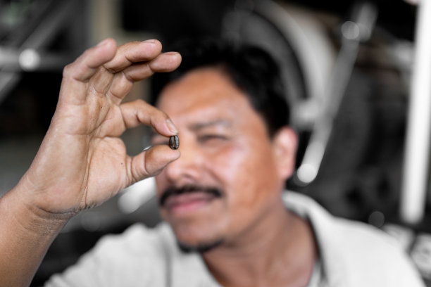 一名西班牙男子正用手拿着一颗咖啡豆图片下载