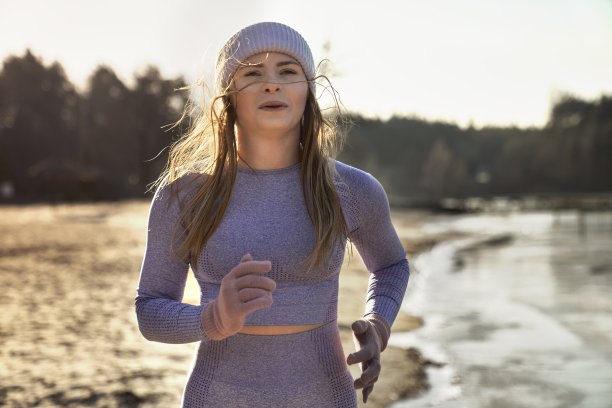 前视图的成年白人妇女慢跑的海滩上的湖在冬天图片下载