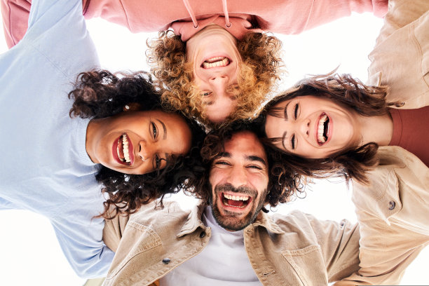 四个快乐的年轻人围成一圈，看着镜头拥抱，玩得很开心。微笑快乐的朋友。图片下载