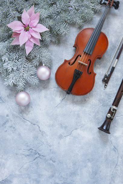古老的小提琴和笛子，冷杉树枝，粉红色的一品红花和圣诞装饰。圣诞节和新年的概念。俯视图，特写在黑暗的混凝土背景。图片下载