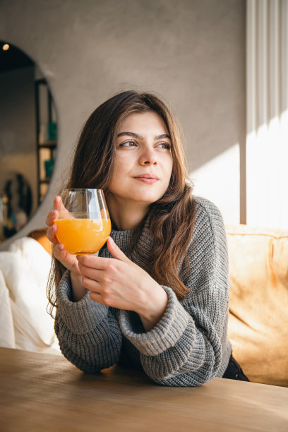 迷人的年轻女子在咖啡馆里拿着一杯橙汁。图片下载