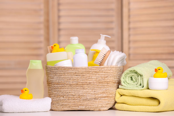柳条篮子与婴儿化妆品，沐浴用品和橡胶鸭子在室内的桌子上图片下载