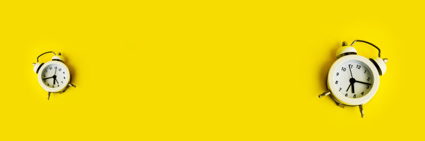黄色背景上的白色闹钟。文本的空白。图片下载