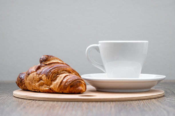 咖啡和羊角面包放在桌上的木托盘里图片下载