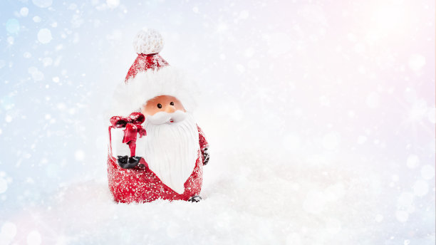 带着礼物的装饰性圣诞老人站在灯光背景下的雪地上。闪闪发光的背景。简单的简约。新年贺卡背景。副本的空间。圣诞家居装饰。图片下载