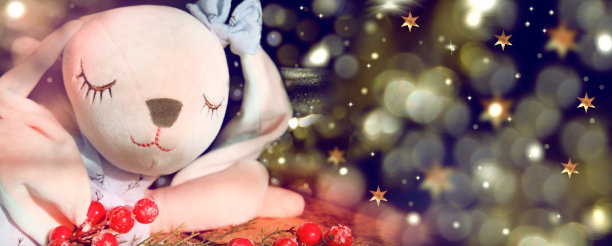 圣诞贺卡与有趣的玩具兔子，睡觉的兔子在模糊星空的夜晚背景。新年装饰玩具。新年快乐图片下载