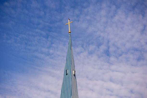 蓝色的天空，淡白色的小云彩和金色的教堂十字架在塔顶的天空背景图片下载