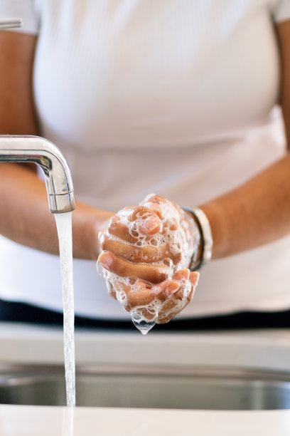 拉丁妇女在厨房水龙头洗手。特写字幕图片下载