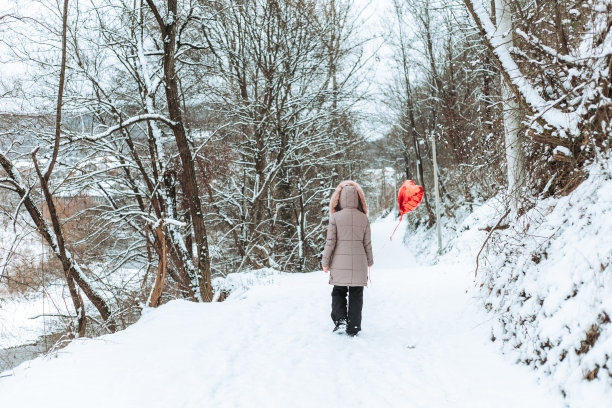 一个女孩走在森林里的路上带着一个红色的氦气球图片下载