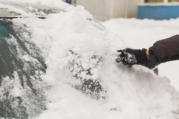 用刷子清理汽车上的积雪。雪下的汽车。冬天的天气。气候。风暴。运输图片下载
