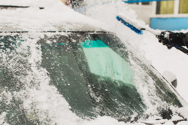 用刷子清理汽车上的积雪。雪下的汽车。冬天的天气。气候。风暴。运输图片下载