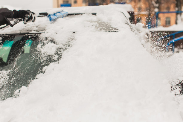 用刷子清理汽车上的积雪。雪下的汽车。冬天的天气。气候。风暴。运输图片下载